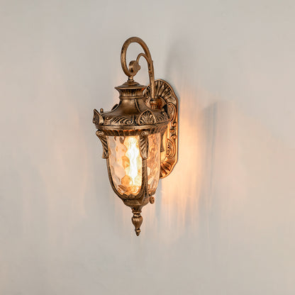 Antique brass metal outdoor wall light on white background with textured water glass shade for elegant porch decor.
