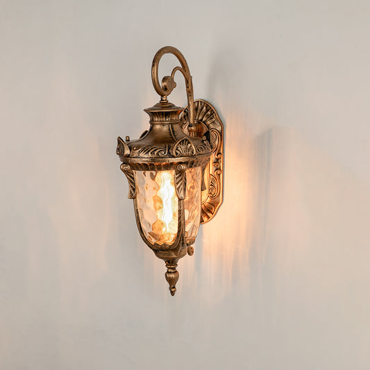 Antique brass metal outdoor wall light on white background with textured water glass shade for elegant porch decor.
