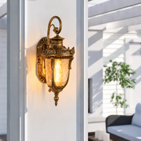 Antique ornate brass metal glass coach lantern wall sconce on white porch pillar for luxury estate courtyard exterior.