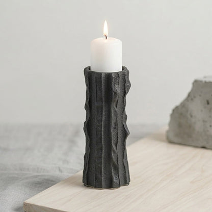 Black ceramic decorative candle holder placed on table with candle modern minimal home decor styling idea.