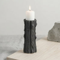 Black ceramic decorative candle holder placed on table with candle modern minimal home decor styling idea.