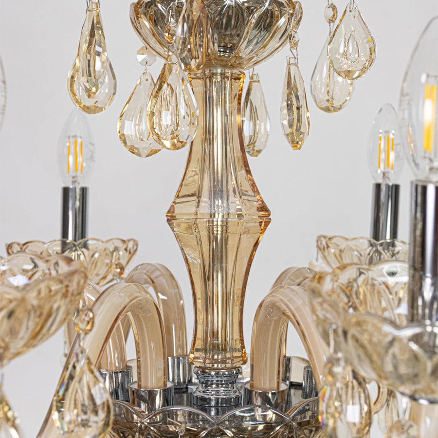 Closeup of golden crystal chandelier with crystal droplets and curved arms perfect for luxury interior ceiling decor.
