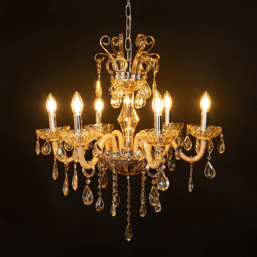Golden crystal chandelier glowing warmly on black background creating a striking luxury ceiling feature.
