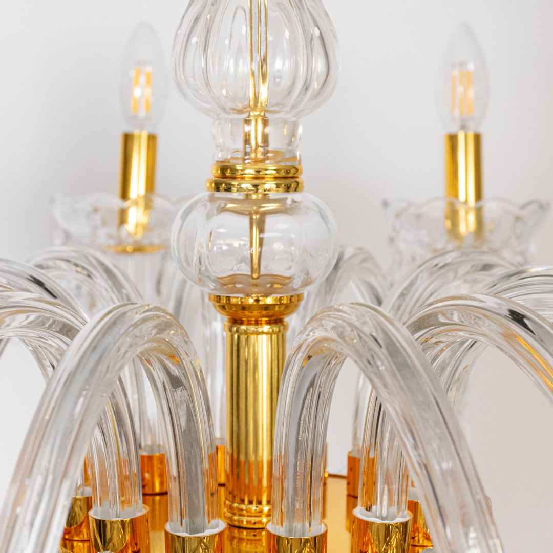 Closeup of chandelier with crystal arms and gold finish highlighting detailed droplets for elegant lighting design.