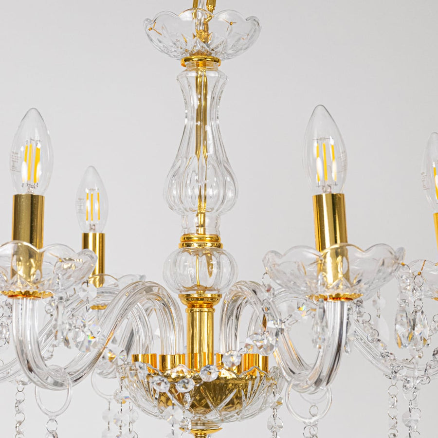 Closeup of crystal chandelier with gold frame glass arms and crystal drops for luxury home decoration.