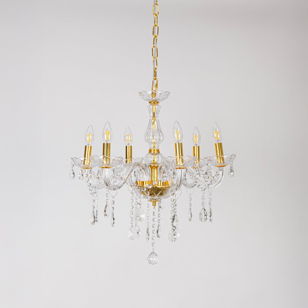 Crystal chandelier with gold frame and glass arms turned off with crystal drops on white background decor.