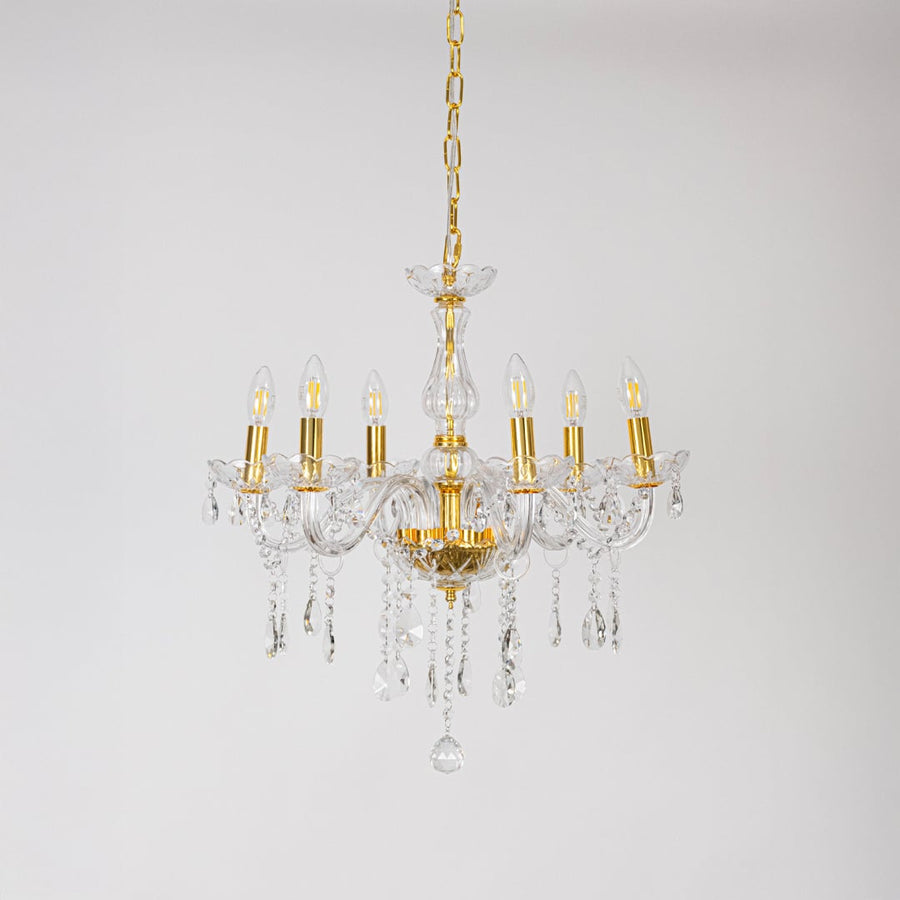 Crystal chandelier with gold frame and glass arms turned off with crystal drops on white background decor.