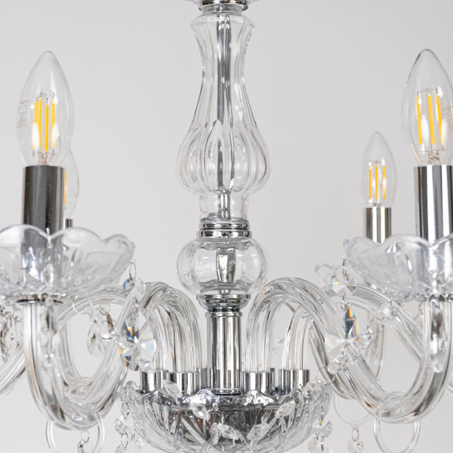 Closeup of crystal chandelier showing candle style bulbs glass detailing and crystal accents for luxury home decor.