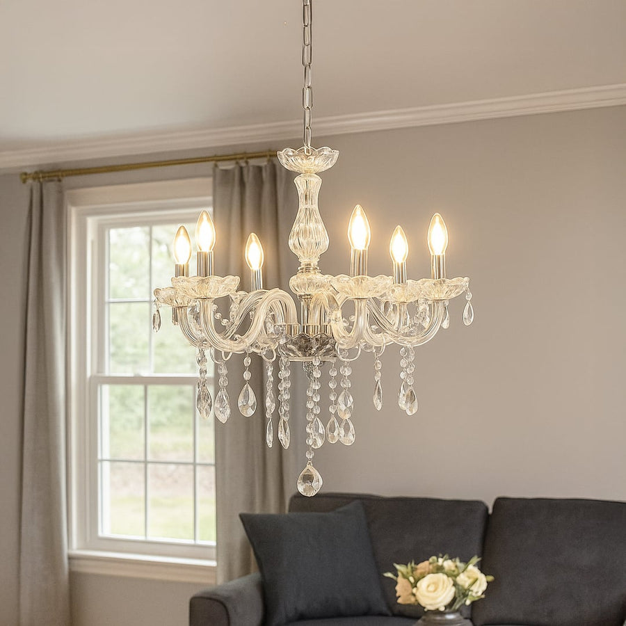 Crystal chandelier glowing above a beige sofa with wall mirror and framed art adding elegance to modern living room.