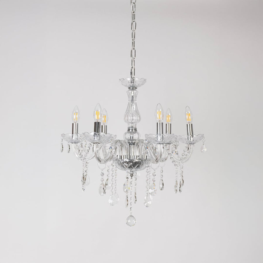Crystal chandelier with lights off showing glass arms and crystal chains photographed on plain white background.