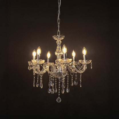 Crystal chandelier with lights on glowing warmly with elegant glass arms and crystal beads against black background.