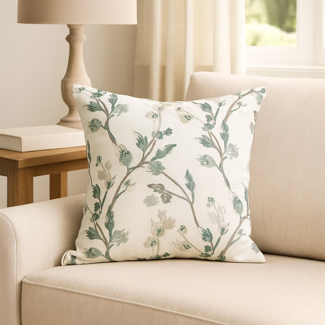Soft cotton cushion cover with green botanical embroidery placed on a beige sofa enhancing home décor with a fresh natural style and a smooth comfortable skin friendly feel.