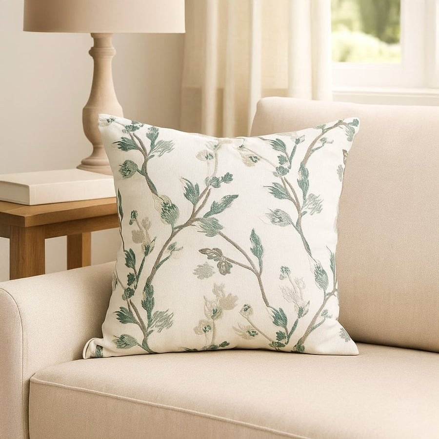 Soft cotton cushion cover with green botanical embroidery placed on a beige sofa enhancing home décor with a fresh natural style and a smooth comfortable skin friendly feel.
