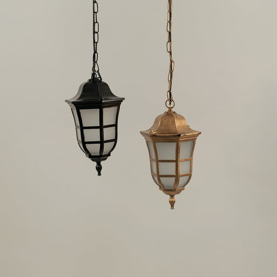 Pair of classic hanging lantern lamps one black and one antique brass finish suspended together with lights off against a plain background.
