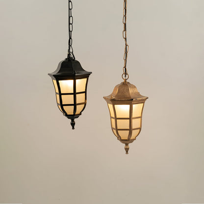 Two classic lantern pendant lights one black and one antique brass hanging together with warm lights on against a plain background.