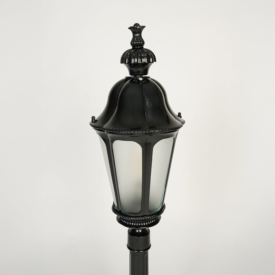 Close view of black outdoor lantern pole light with glass enclosure showcasing classic weather resistant exterior lighting design.

