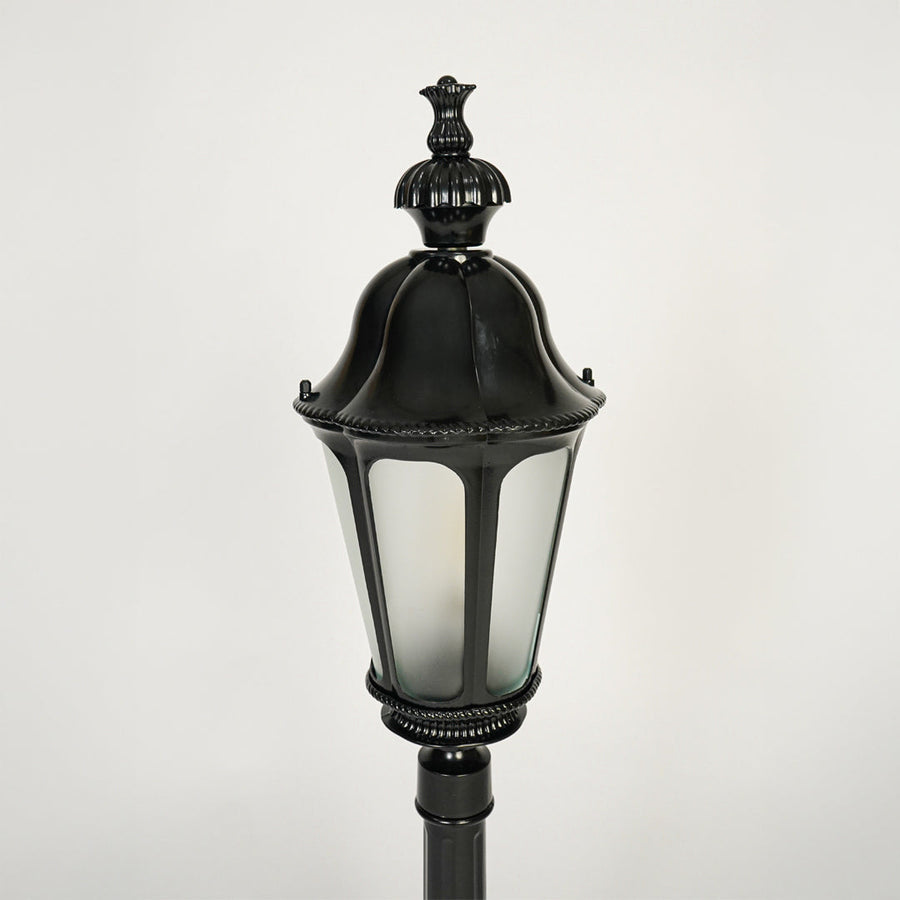 Close view of black outdoor lantern pole light with glass enclosure showcasing classic weather resistant exterior lighting design.

