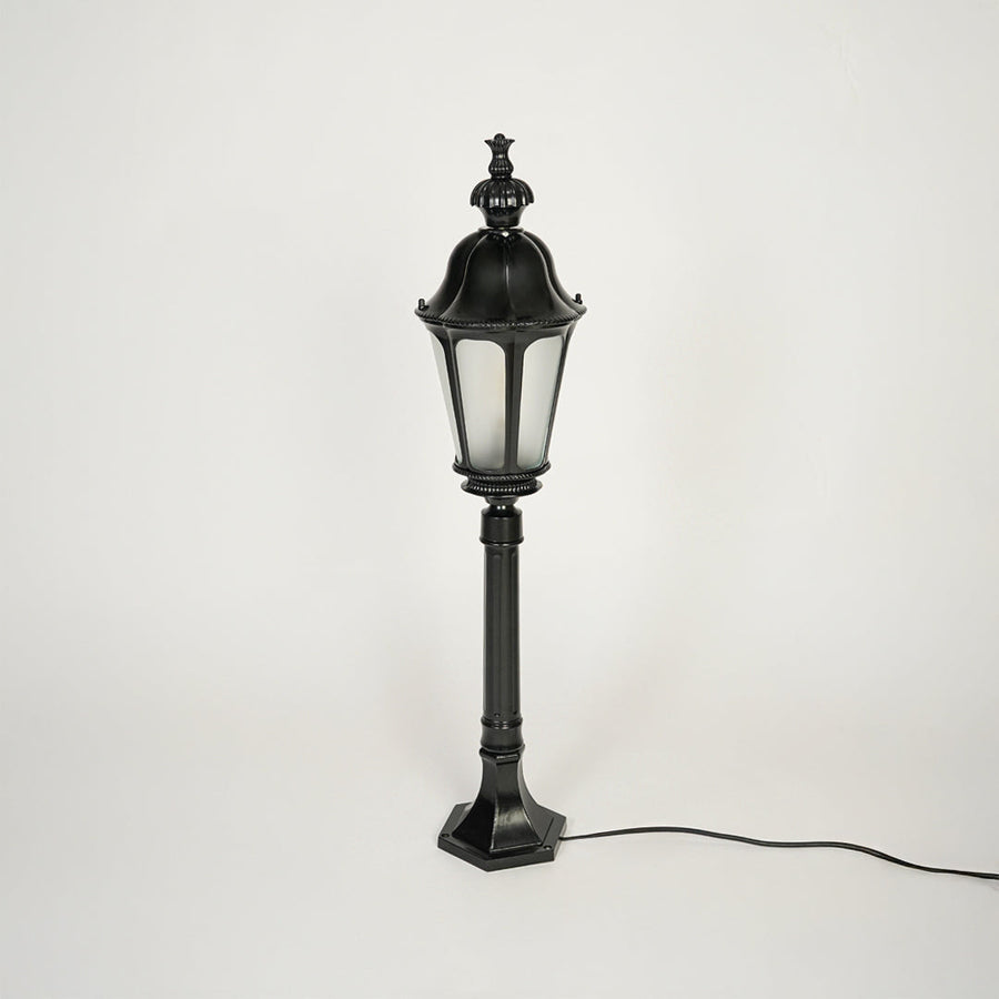 Traditional outdoor pole light with decorative top and black metal body on clean background ideal for garden or patio lighting.