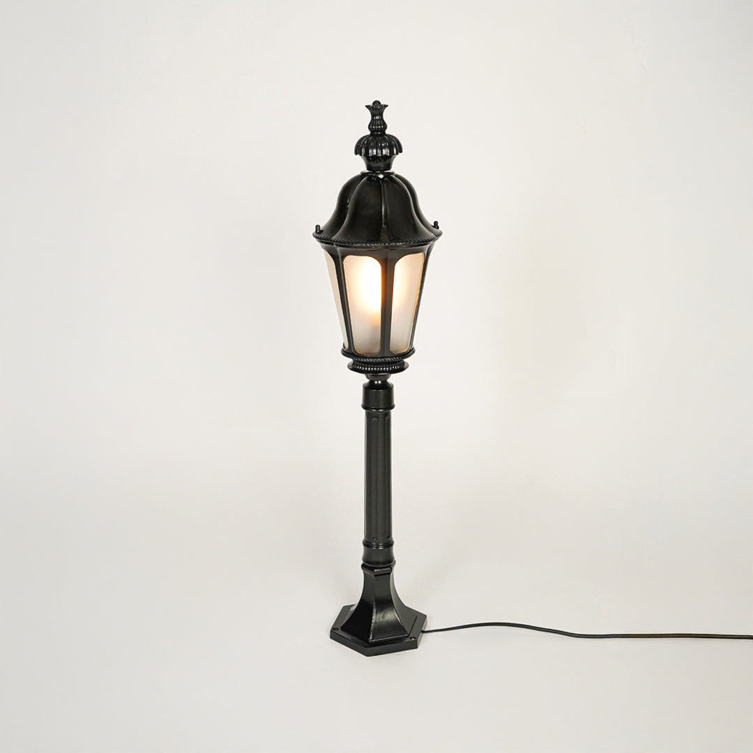 Vintage style black metal garden lamp post with clear glass panels on neutral background perfect for outdoor lawn or driveway lighting.