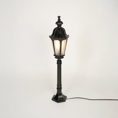 Vintage style black metal garden lamp post with clear glass panels on neutral background perfect for outdoor lawn or driveway lighting.