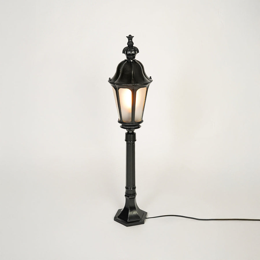 Vintage style black metal garden lamp post with clear glass panels on neutral background perfect for outdoor lawn or driveway lighting.
