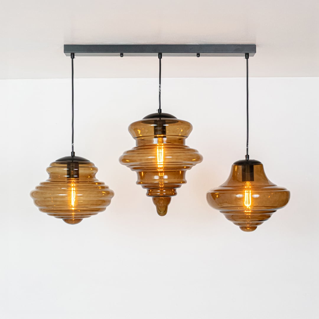 Amber glass and gold metal pendant lights showcasing artistic designs for modern dining spaces.