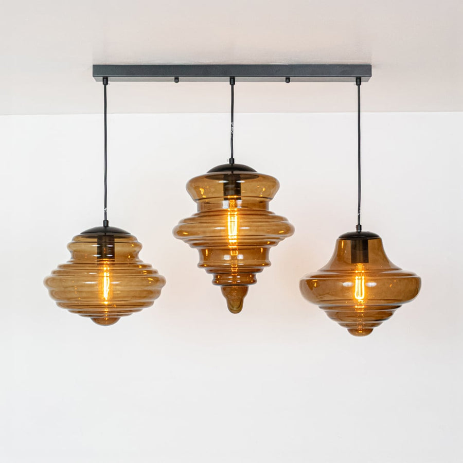 Amber glass and gold metal pendant lights showcasing artistic designs for modern dining spaces.