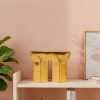 Gold metal decorative sculpture placed on shelf modern designer showpiece for living room console home decor styling.