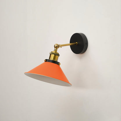 A modern wall-mounted sconce with a bright orange cone-shaped shade, a brass-colored adjustable arm, and a round black wall plate, shown against a plain off-white wall.