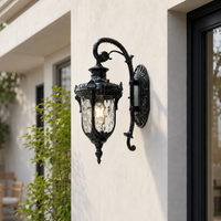 Ornate black iron decorative scroll carriage wall lantern with crackle glass on white stucco exterior for luxury home porch.