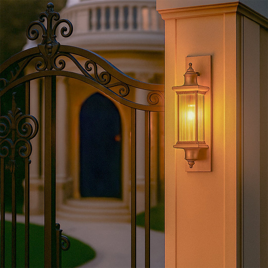 Antique bronze outdoor wall lantern lifestyle image illuminating a warm light on a gate pillar placement for decor.