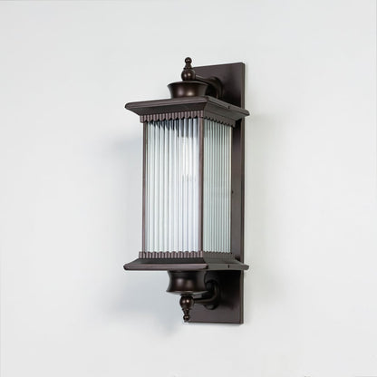 Black metal outdoor wall light on white background with ribbed glass shade for modern patio wall decor.