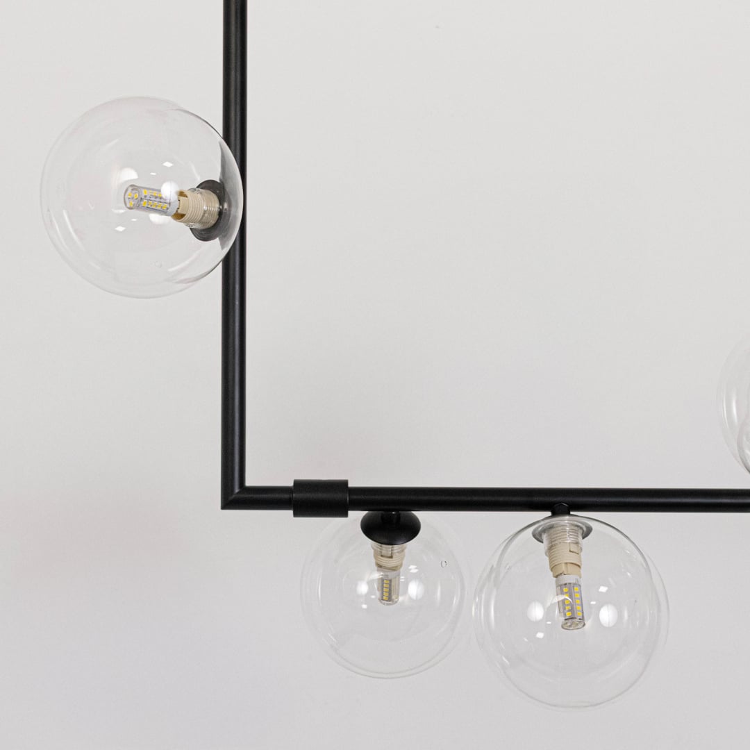 Closeup of black linear chandelier with clear glass globes highlighting detailed metal finish and elegant globe design.