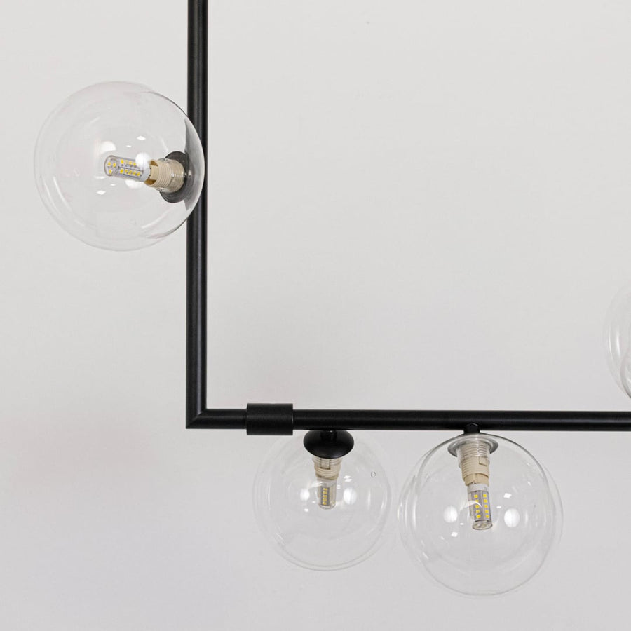 Closeup of black linear chandelier with clear glass globes highlighting detailed metal finish and elegant globe design.