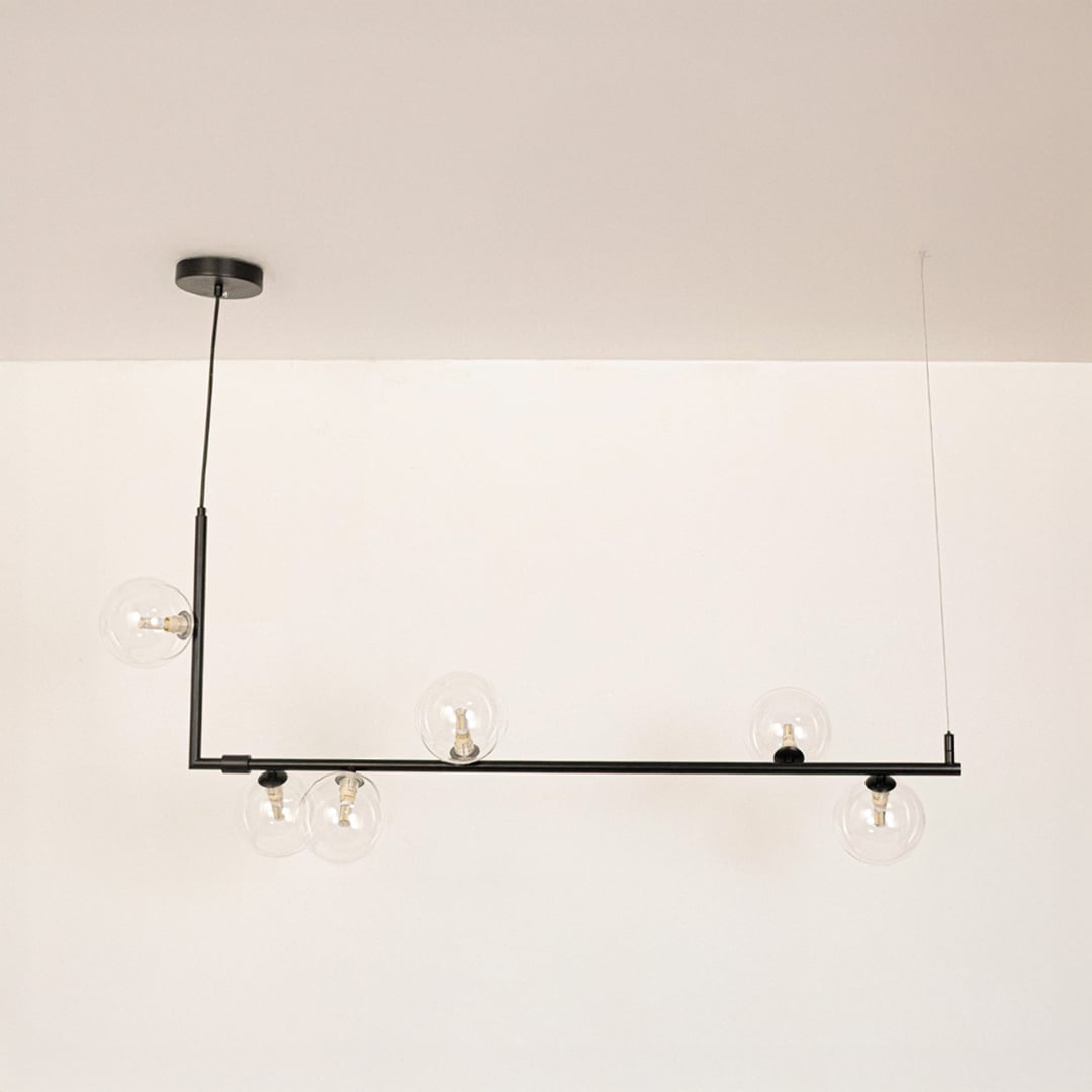 Black linear chandelier with clear glass globes displayed on a white background with lights off showing clean form.