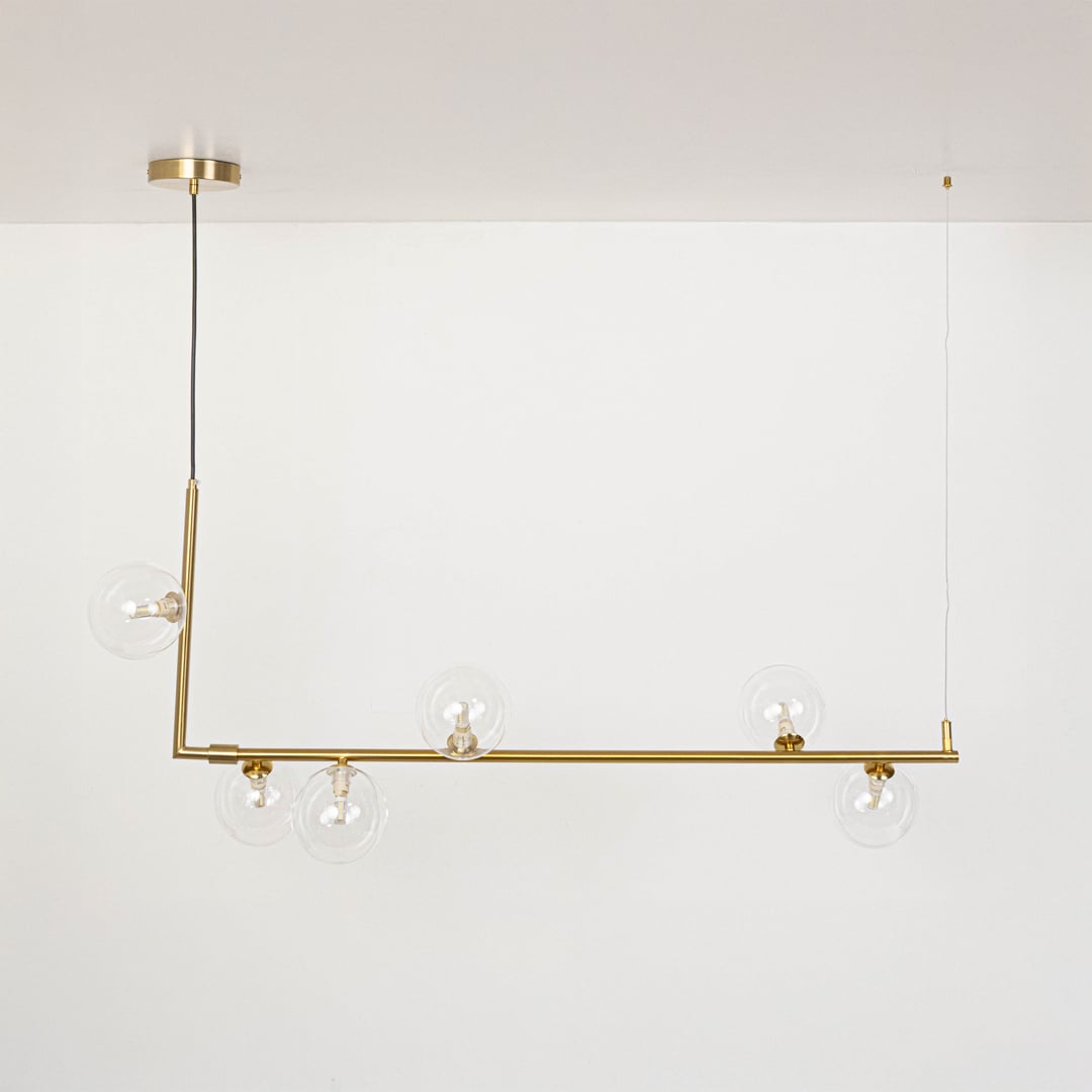 Gold linear chandelier with clear glass globes displayed on a white background with lights off showing clean form.
