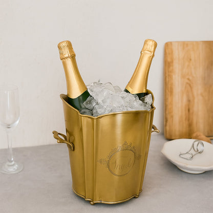 legant gold brass ice bucket with scalloped rim holding two champagne bottles and ice cubes on a modern table for party celebration.