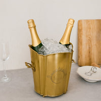 legant gold brass ice bucket with scalloped rim holding two champagne bottles and ice cubes on a modern table for party celebration.