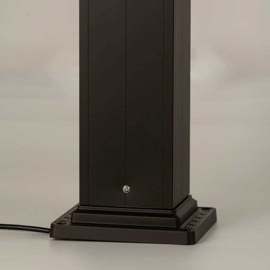A detailed look at the lamp’s upper section highlighting the decorative finial the sloped roof and the geometric frame design surrounding the frosted glass panel.