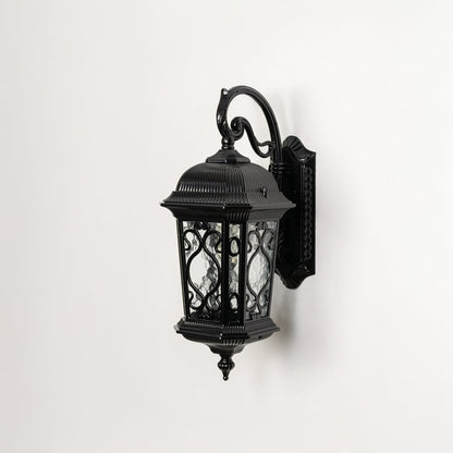 Light off white background displays black metal outdoor wall lantern showcasing ornate design glass texture and sturdy build.