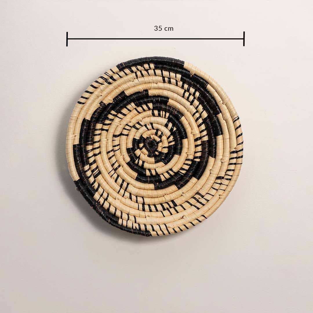 Dimension image of handcrafted black cream seagrass wall basket with swirling vortex spiral pattern for bohemian wall decor.