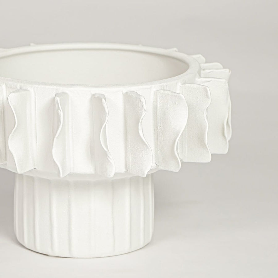 Closeup of matte white ceramic bowl vase with detailed textured rim ideal for elegant home decor shelf styling.