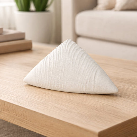 Modern ceramic decor sculpture in white textured finish placed on wooden table in living room styling.