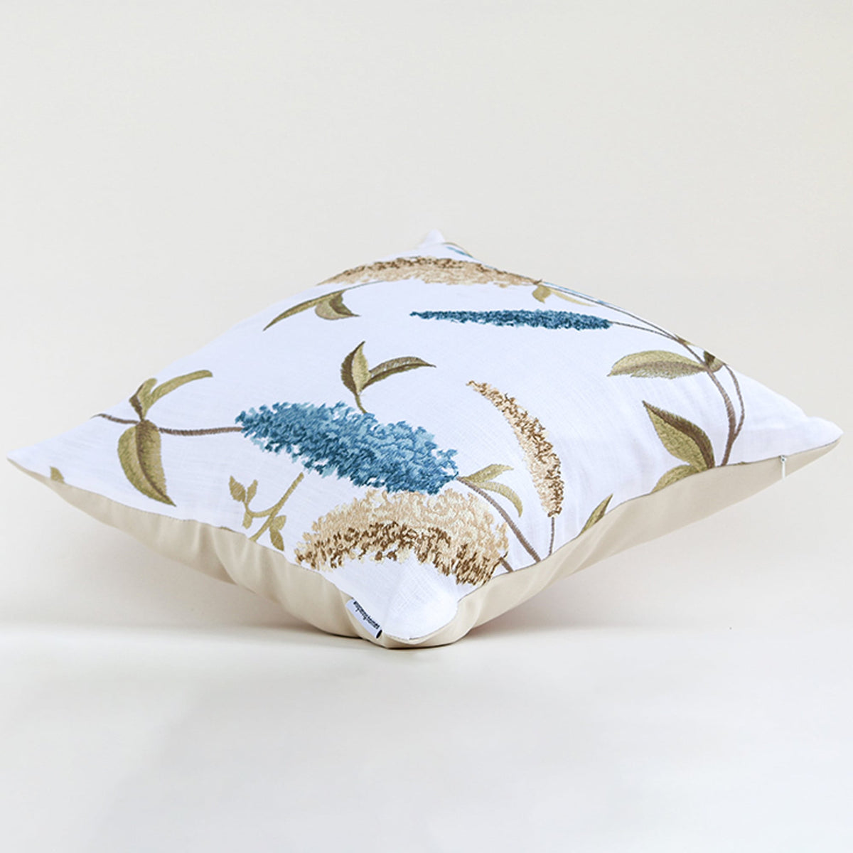 White cushion cover with blue floral botanical print soft fabric texture and elegant decorative pillow styling on white background.