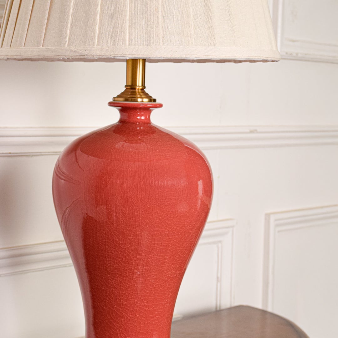 Glossy red ceramic table lamp base with gold detailing showcasing artisan craftsmanship and luxury interior styling.