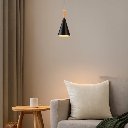 Modern black metal and light wood pendant light fixture hanging over a grey sofa and wood side table in a cozy living room setting.