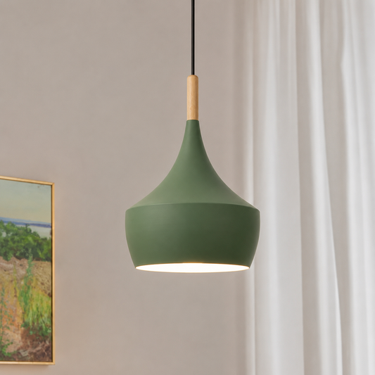 A modern pendant light with a matte sage green shade, a light natural wood neck, and a black cord, shown hanging in a room with white curtains and a framed landscape painting on the wall.