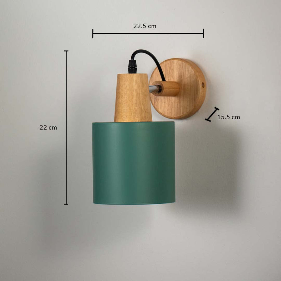 Wall lamp with matte dark green cylinder shade wooden base and black cord shown with size 22 cm height 22.5 cm width and 15.5 cm depth.