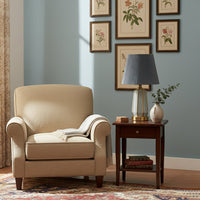 Table lamp with metal base and fabric shade in blue placed beside armchair creating warm ambient lighting for living room decor.