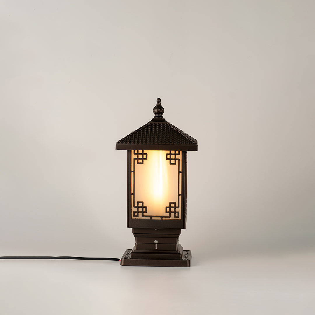 Vintage black outdoor gate light with warm glowing glass panels for elegant exterior decor use.